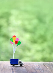 decorative air balloons and little truck toy, green natural background. Concept for visualization...