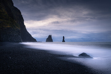 Stormy morning at the shore of lonely Reynisfjara black sand beach looking to Reynisdrangar cliff in Iceland