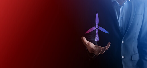 Businessman holding an icon of a windmill that produces environmental energy. Dark background. Neon red , blue light