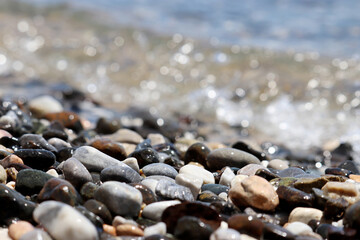 Wet pebble stones on blurred background of sea waves. Beach vacation at summer