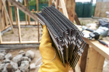 Nails in carpenter hand with nail gun on the background