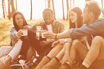 Sitting and resting. Group of young people is traveling together in the forest at daytime