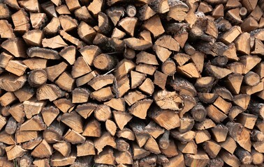Stacked firewood background. Firewood pattern. Wood saving wall. Stock of wood for kindling a fireplace for the winter. Natural materials background.