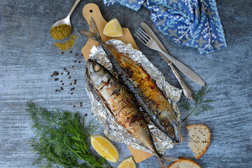 Appetizing grilled fish, lemon and spices on a blue background. View from above
