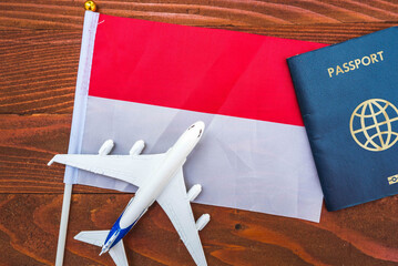 Flag of Indonesia with passport and toy airplane on wooden background. Flight travel concept 