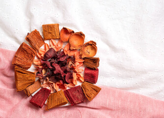 On the left side dried flowers and petals of buds on a pink and white fabric close-up.