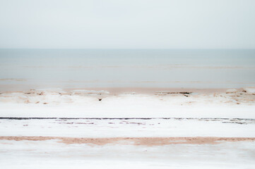Seaside in winter. Intentional blur. Snow mixed with sand at seaside. Beach in winter