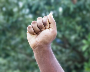 Men strong fist hand stretching up on soft green bokeh background