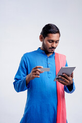 Young indian farmer using smartphone and bank card on white background.