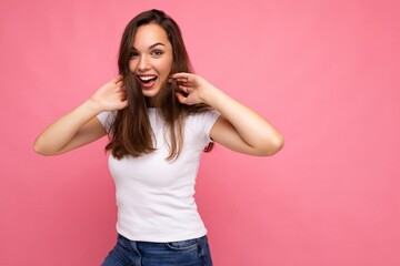 Fototapeta na wymiar Portrait of positive cheerful fashionable woman in casual white t-shirt for mock up isolated on pink background with copy space