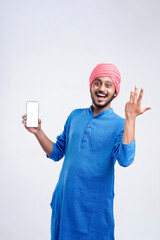 Young indian farmer showing smartphone and giving expression on white background.