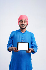 Young indian man in traditional wear and showing tablet over white background.
