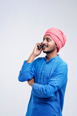 Young indian farmer talking on mobile phone over white background.