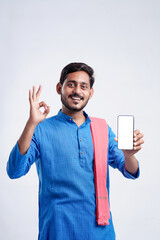 Young indian farmer showing smartphone and giving expression on white background.