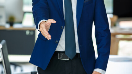 Cheerful Asian businessman reaching out hand for handshake