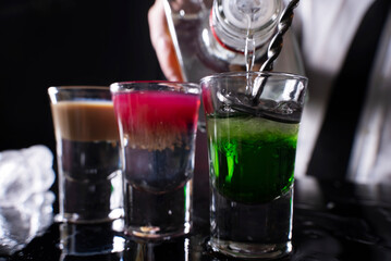 Barman preparing cocktail shots at the bar counter. Barman mixing drinks at the night club..
