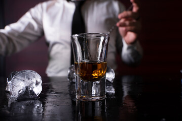 Barman preparing cocktail shots at the bar counter. Barman mixing drinks at the night club..
