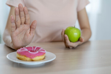 Good health food and diet. Women reject junk food or unhealthy foods such as doughnuts and choose healthy foods such as green apple.