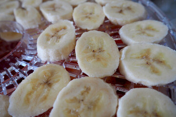 round sliced raw bananas are lying in the dryer on the side. cooking banana chips at home . sweets at home