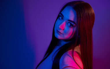 Fashionable young woman standing in the studio with neon light