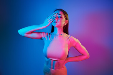 Slim body. Fashionable young woman standing in the studio with neon light