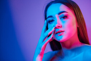 Neutral facial expression. Fashionable young woman standing in the studio with neon light