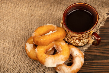 Fresh homemade doughnuts with powdered sugar and a earthenware mug of tea. Close-up Selective focus.