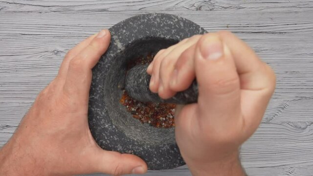 The top view of a pestle spices, peppers and sea salt in the grey stone mortar
