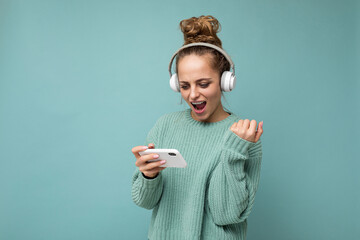 Attractive emotional positive young woman wearing blue sweater isolated over blue background...
