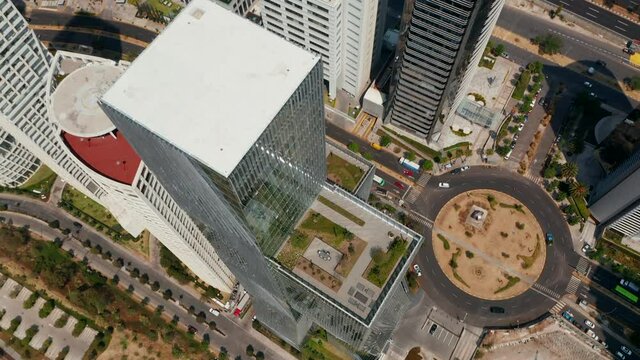 Fly over modern tall Paradox Torre building. Camera tilt down shot. Top down view of surrounding streets and park. Mexico City, Mexico.