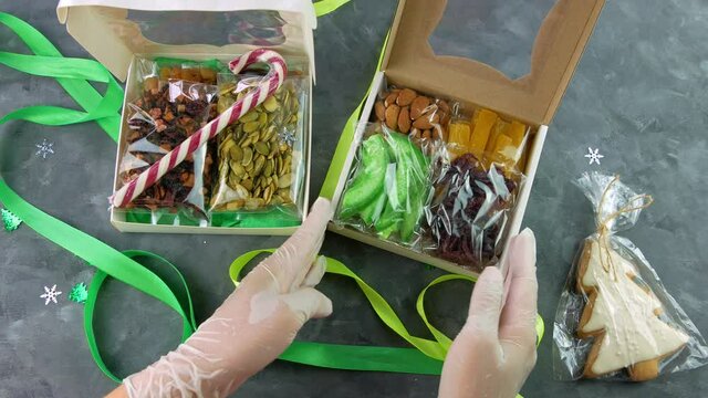 Girl wraps gift box with dried fruits nuts individually wrapped set. Healthy food diet. Christmas celebration holidays preparing eco natural snack in female hands.Conscious consumption homemade sweets