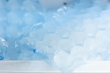 Closeup of ice cubes made in plastic bags seen in a freezer.