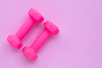 Top view of pink dumbbells on pink background. Copy space