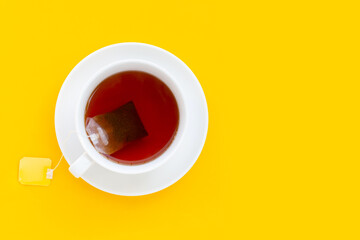 White cup of tea on yellow background
