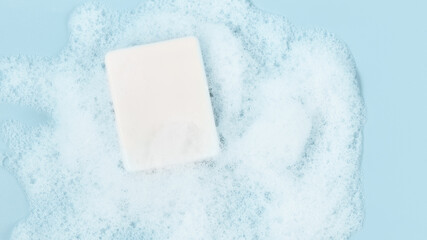 hand made soap in lush white foam on a light blue background. cosmetic background panoramic banner