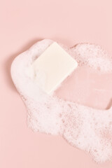 hand made soap in lush white foam on a pink background. cosmetic background minimalistic concept. vertical frame