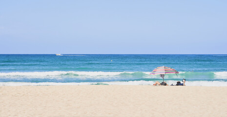 Fototapeta na wymiar Summer concept. Two umbrellas, beach and blue sea on a beautiful sunny day