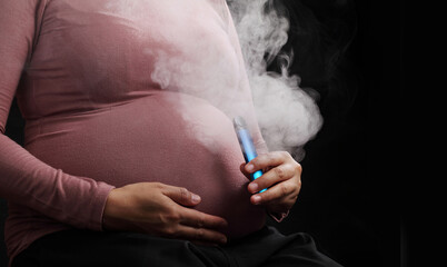 Close up pregnant woman smoking e-cigarette on black background