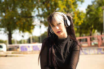 Portrait of young and beautiful girl with heterochromia, pigtails, white headphones and punk style...