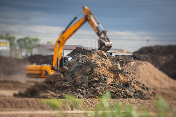 Yellow heavy excavator and bulldozer excavating sand and working during road works, unloading sand...