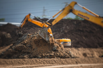 Yellow heavy excavator and bulldozer excavating sand and working during road works, unloading sand during construction of the new road © tsuguliev