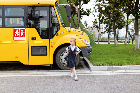 Back to school. Little girl from elementary school outdoor near yellow bus. Kid going learn new things 1th september