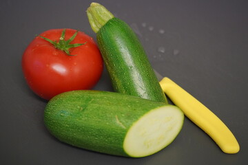 Fresh vegetables from the garden for a delicious dinner recipe. Beautiful bright red tomato and a green zucchini. 