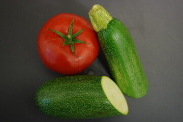 Fresh vegetables from the garden for a delicious dinner recipe. Beautiful bright red tomato and a green zucchini. 