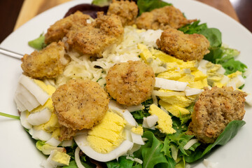 Fried shrimp, made using an air fryer, atop a bed of spinach, mixed greens, hard boiled eggs, and Mozzarella cheese