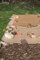 Cardboard placed on grass with old bricks on top with barck chippings to creat a new gardening or farming plant bed or path