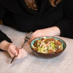 Vegetarian salad, Healthy eating for weight loss. Female hands holding a fork before bowl of dish with mushrooms and rye bread on table. Copy space. Soft focus.