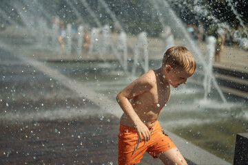 cute little boy running in splashing fountain in Saint petersburg, Russia