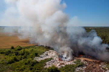 Wild fire at a trash dump. White and gray smoke from burning rubbish on the town dump