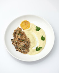 Potatoes with mushrooms. Mashed potatoes with fried champignons and herbs. Food plate isolated on white background. Top view.